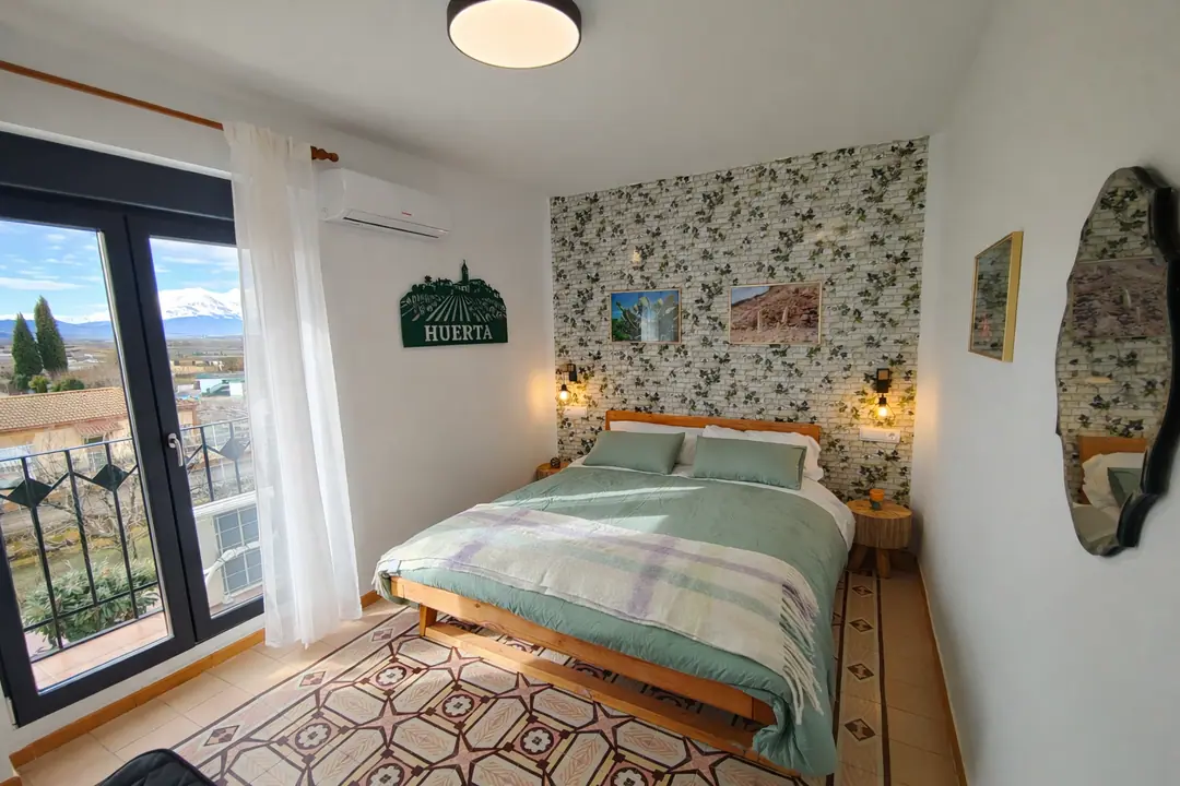 Habitación Huerta con ropa de cama verde y vistas al Moncayo desde el balcón